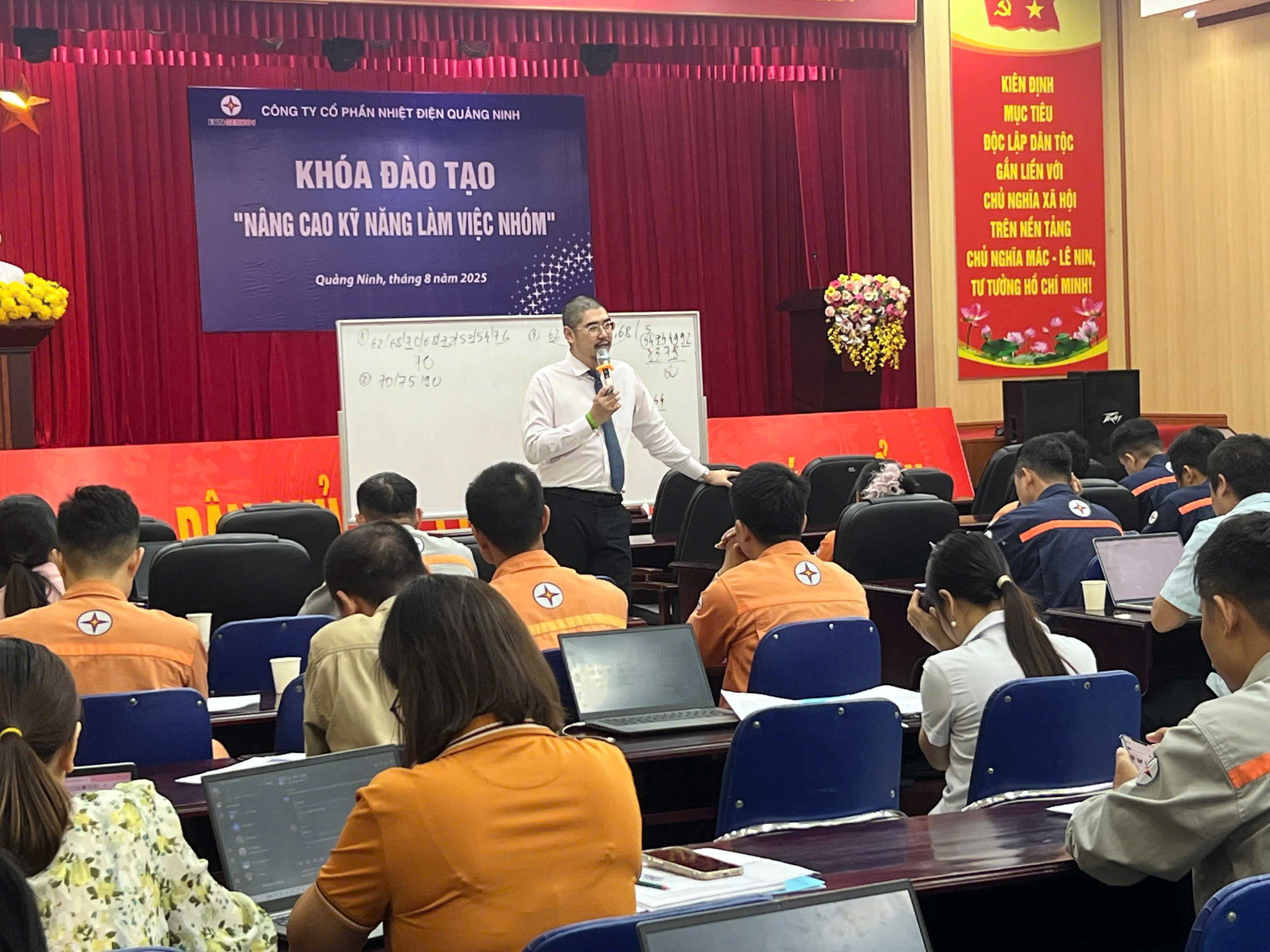 A person speaking into a microphone in front of a group of peopleAI-generated content may be incorrect.